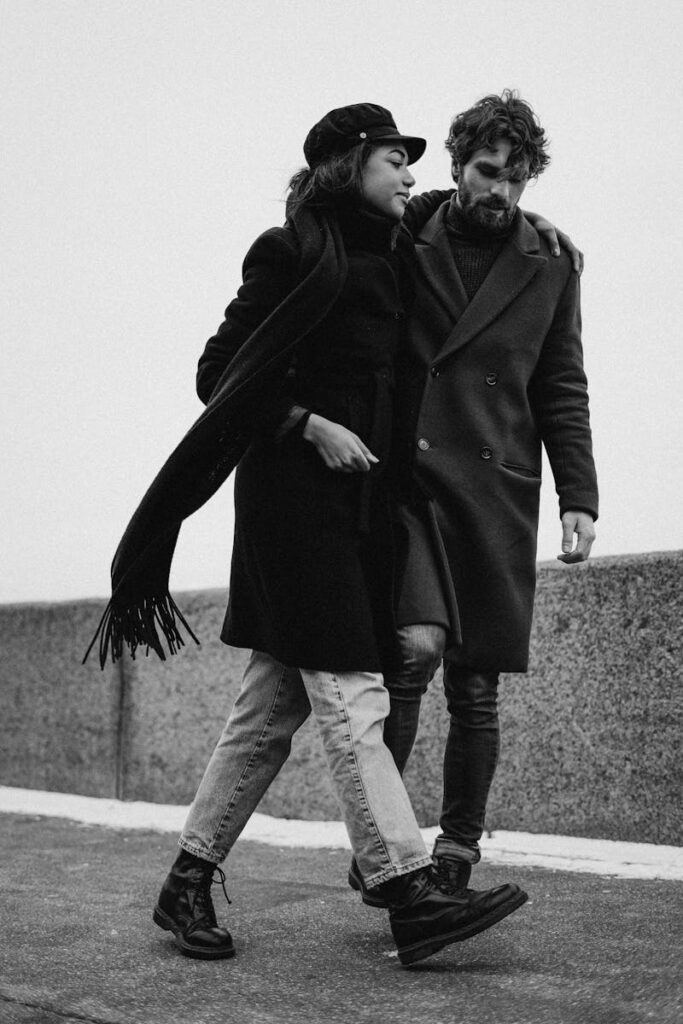 Romantic black and white image of couple walking on a winter day, embracing affectionately.