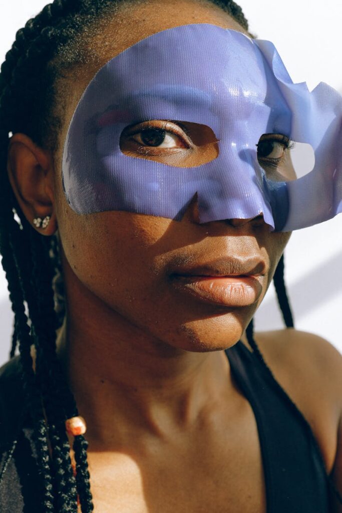 Close-up portrait of an African American woman wearing a blue mask and braided hair.