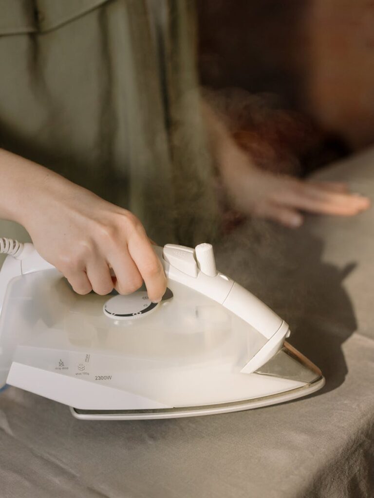 A detailed close-up of a hand using an iron on a cloth surface, evoking home comfort.
