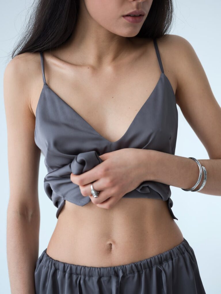 Elegant young woman showcasing her fit physique in modern gray attire against a white background.