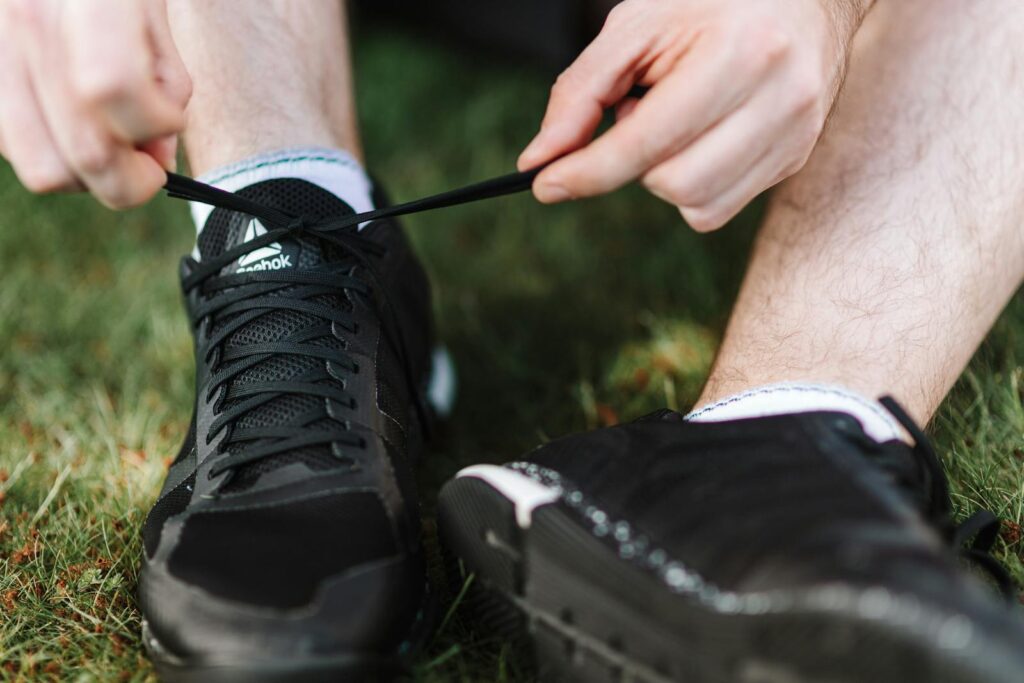 Close-up of a person tying black athletic shoes on grass, highlighting active lifestyle.