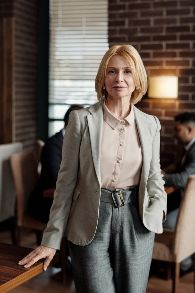 Professional businesswoman in a tailored blazer and trousers, standing confidently indoors.
