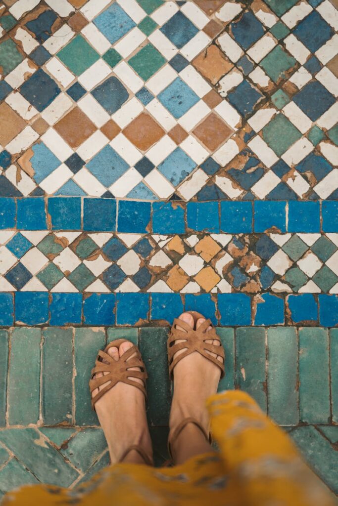 Top-down view of sandals on intricate Moroccan mosaic tiles, showcasing traditional patterns.