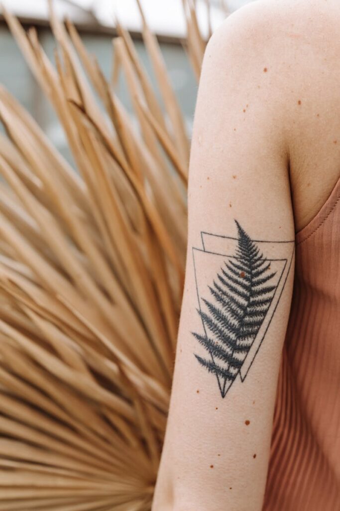 Detailed view of geometric fern tattoo on an arm with natural background.