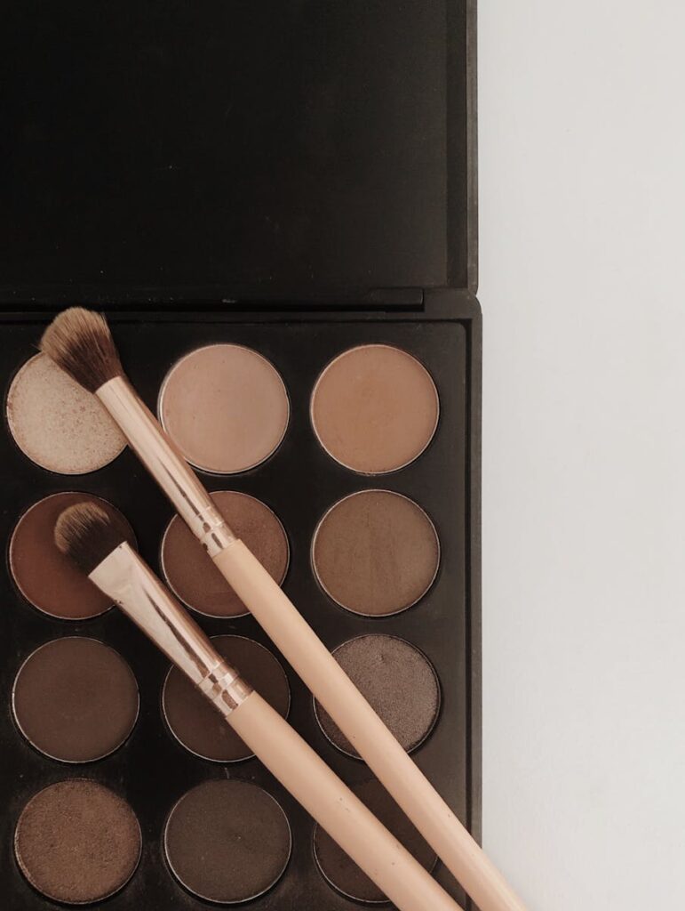 A neutral eyeshadow palette with makeup brushes arranged on top, perfect for beauty and cosmetics themes.