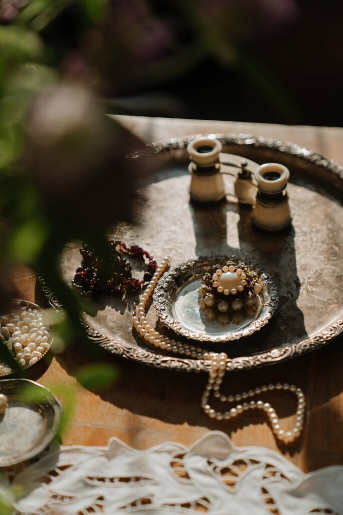 Flat lay of vintage jewelry, pearls, and binoculars on a silver tray, evoking Russian elegance.