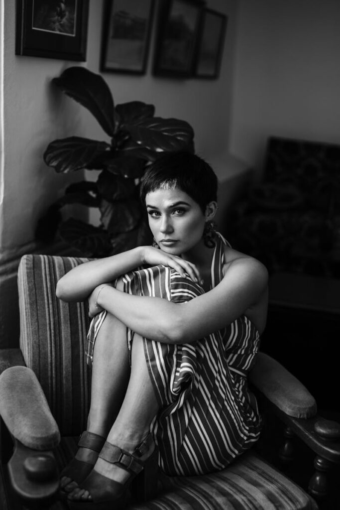 Monochrome portrait of a stylish woman sitting in an armchair with a calm expression.