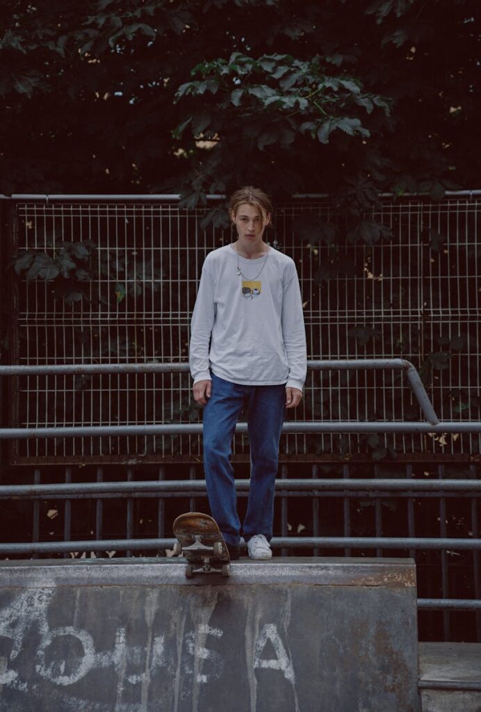 Teenager stands confidently on a skate ramp with a skateboard in an urban park.