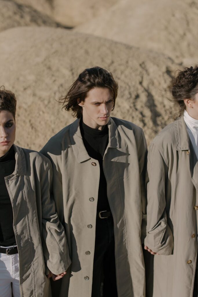 Stylish group wearing trench coats in an outdoor desert setting, showcasing modern fashion.