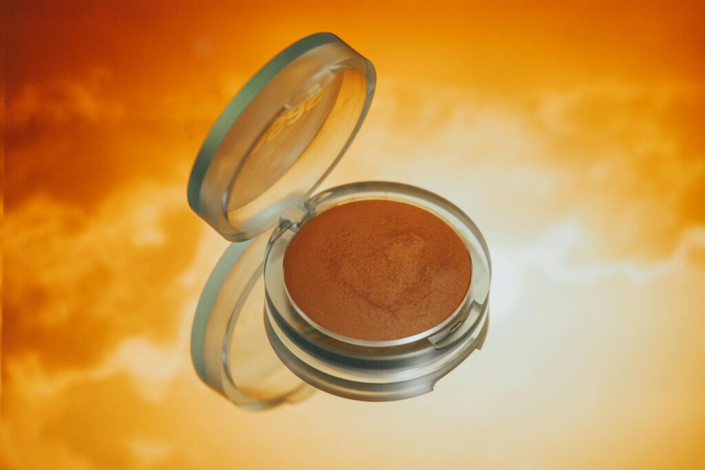 Bronzer illuminating a vibrant orange backdrop, ideal for makeup visuals.