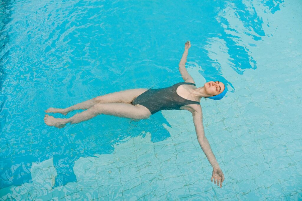 A woman floats peacefully in a swimming pool, enjoying a sunny summer day.