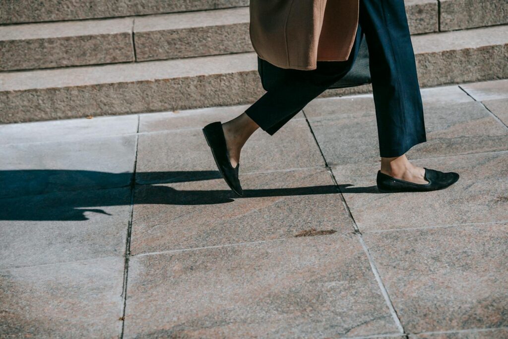 Elegantly dressed woman walking on a city sidewalk in fall.