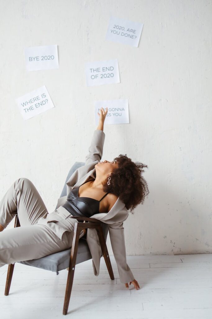A woman reclining in a chair with signs expressing exhaustion of 2020 on the wall.