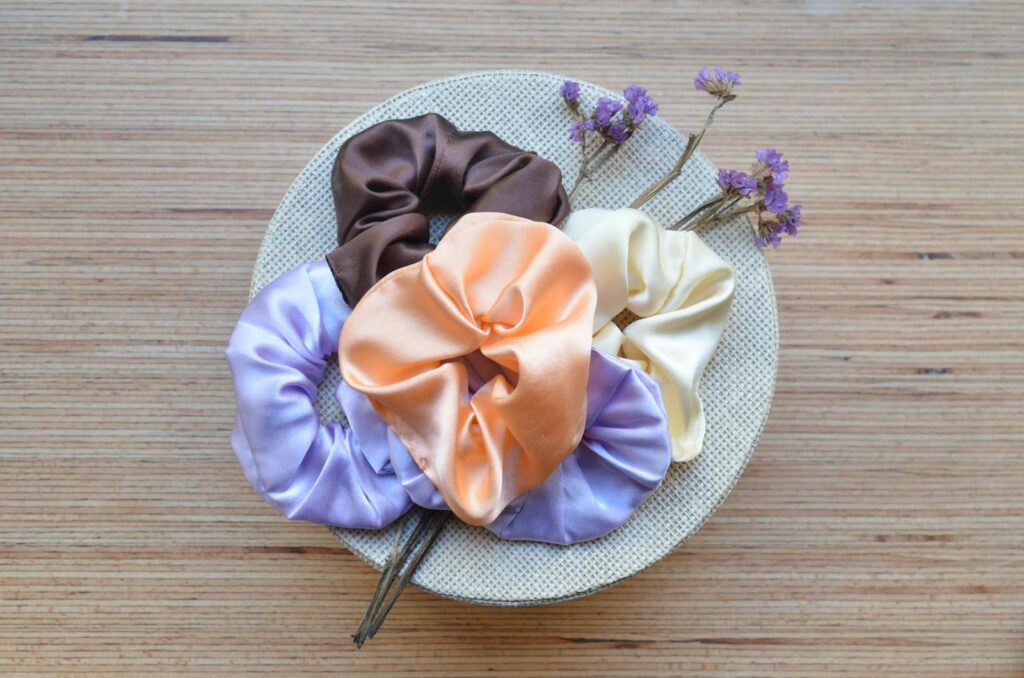 A creative arrangement of satin scrunchies and dried flowers on a woven mat for a decorative touch.