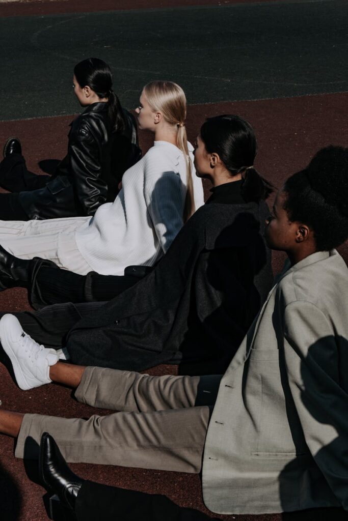 Four women sitting outdoors on a sunny day, showcasing modern fashion style.