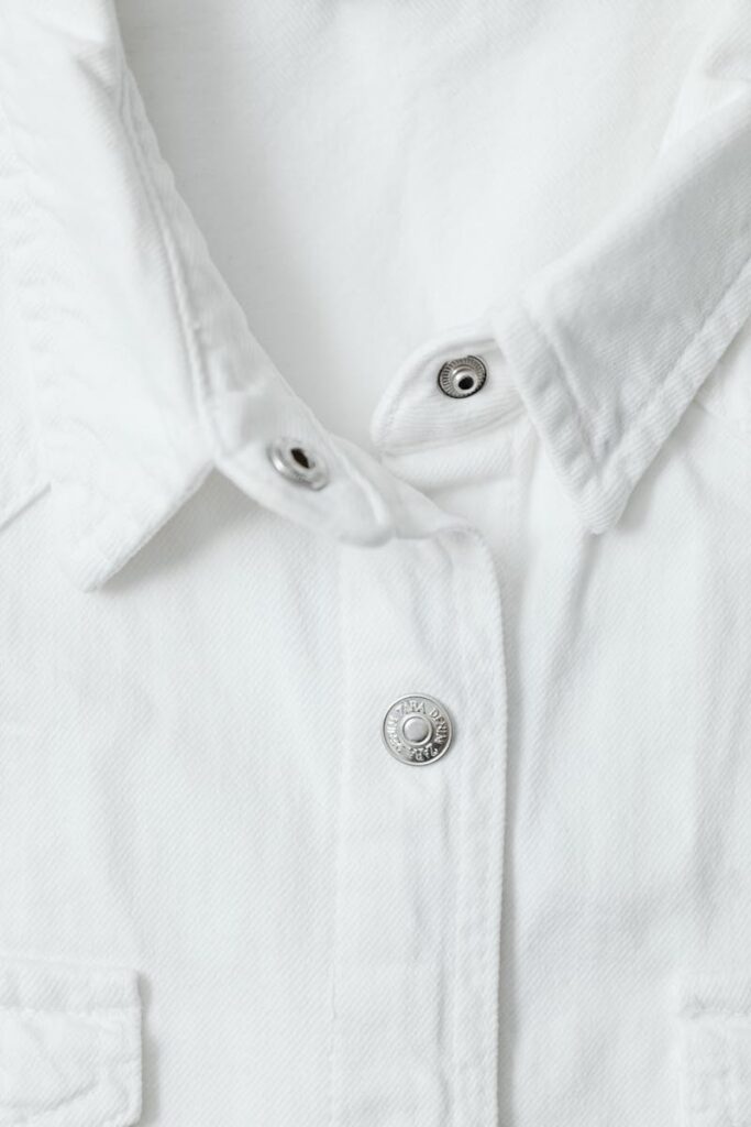 Detailed view of a white shirt's buttoned collar showcasing fabric texture.