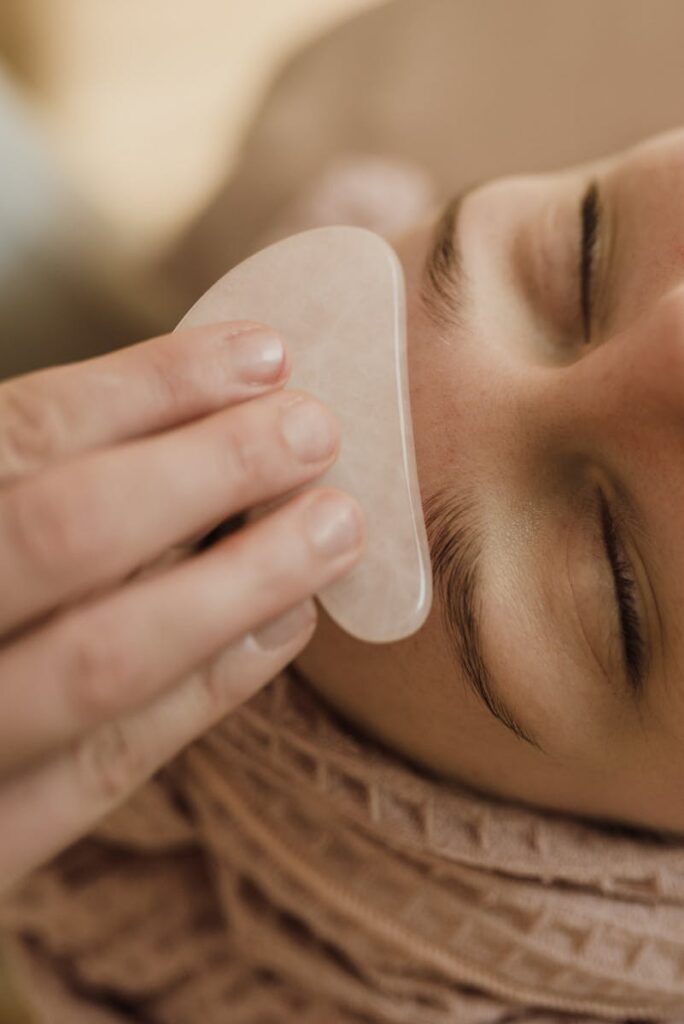 Close-up of a woman receiving a soothing gua sha facial massage indoors.