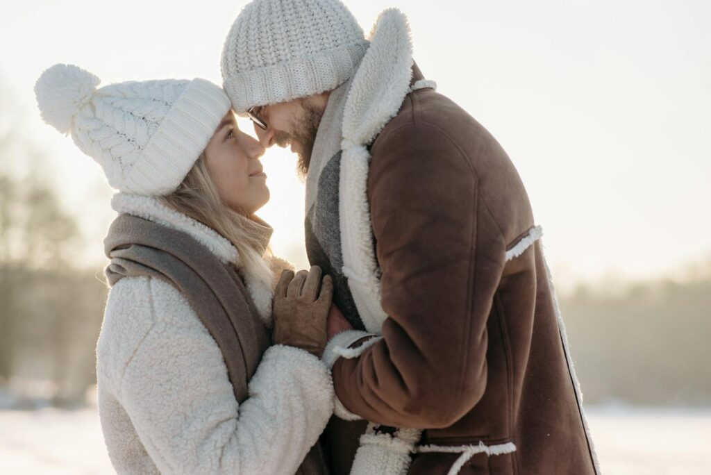 Close-up of a loving couple in cozy winter clothes, sharing a tender moment outdoors.