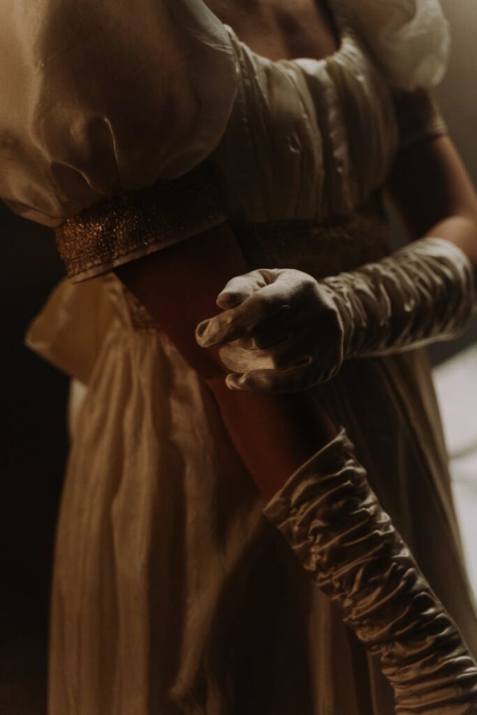 Close-up of a woman in a 19th-century empire style dress with silk gloves.