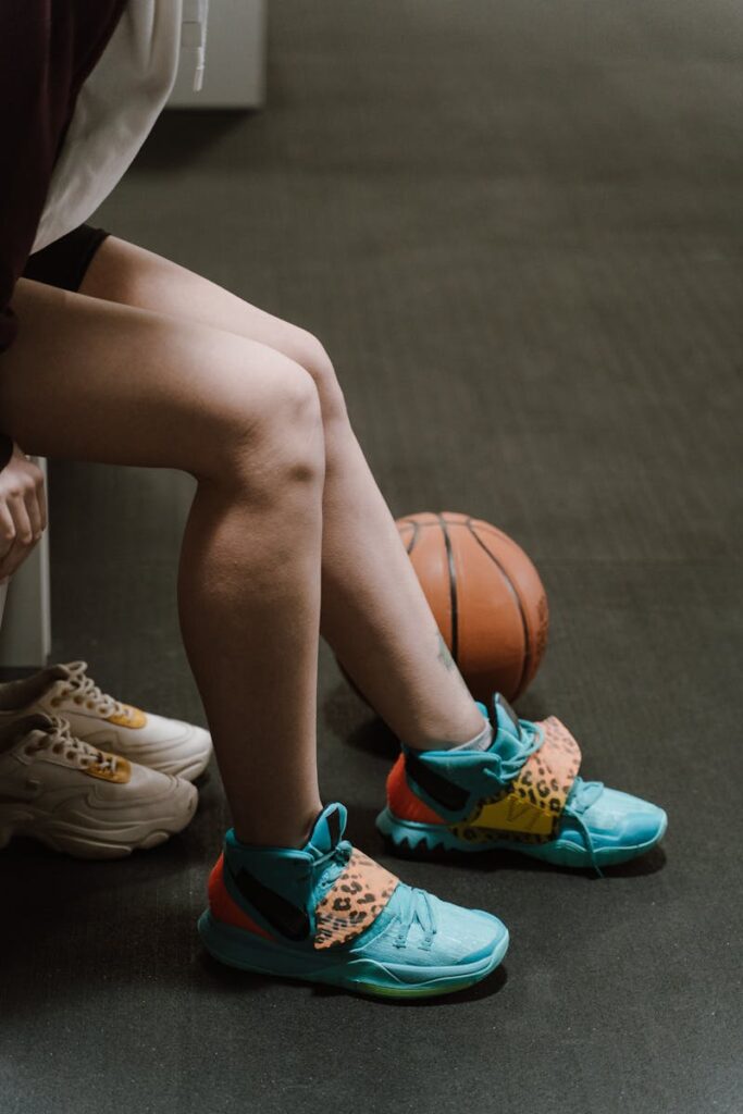 A sportswoman prepares for the game in a changing room, showcasing her colorful sneakers.