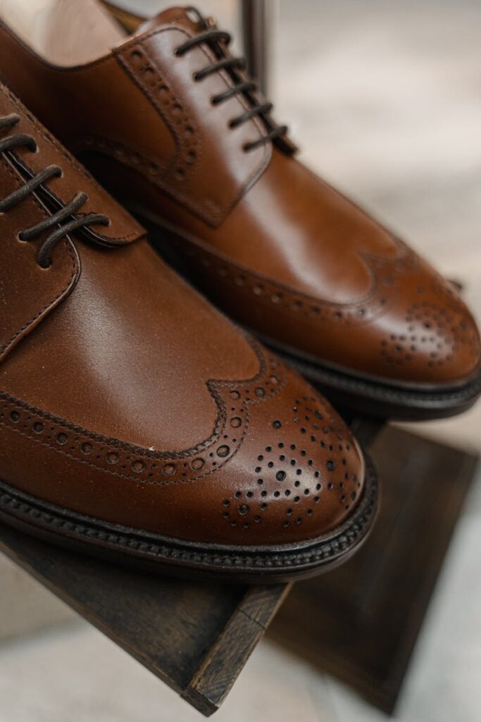 Detailed close-up of classic brown leather brogue shoes on display.
