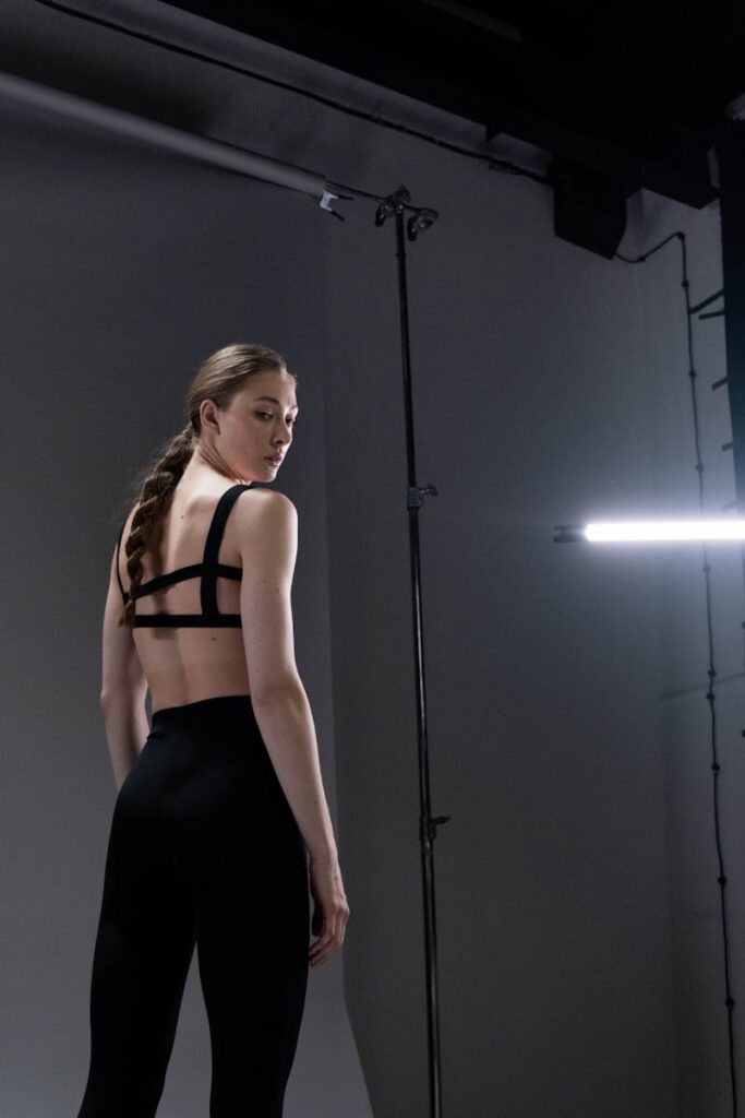 Studio shot of a woman in black activewear with braided hair, modern lighting.