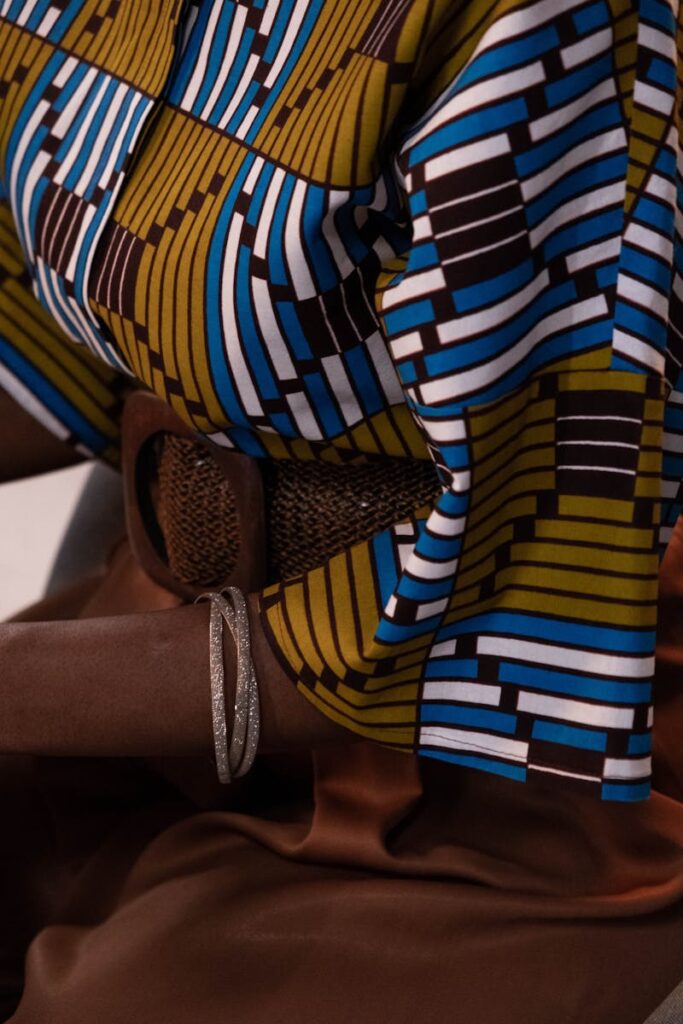 Close-up of a person wearing a colorful geometric patterned blouse and brown skirt, showcasing fashion details.