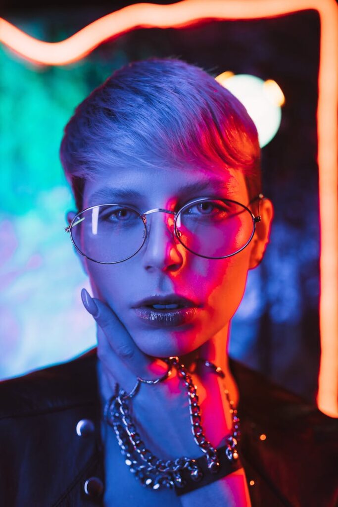 Modern portrait of a woman in neon lighting wearing glasses and jewelry.
