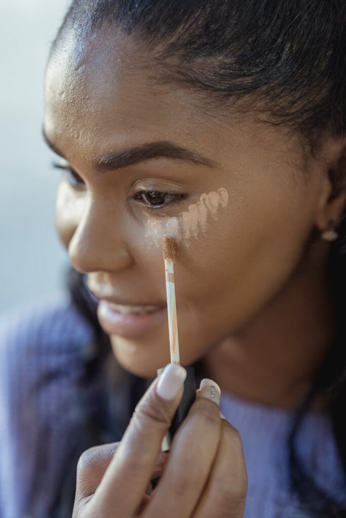 Close-up of a young woman applying concealer, highlighting her skincare routine for a flawless complexion.