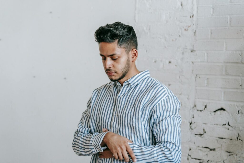 A young man performing salah while standing in a peaceful indoor setting.