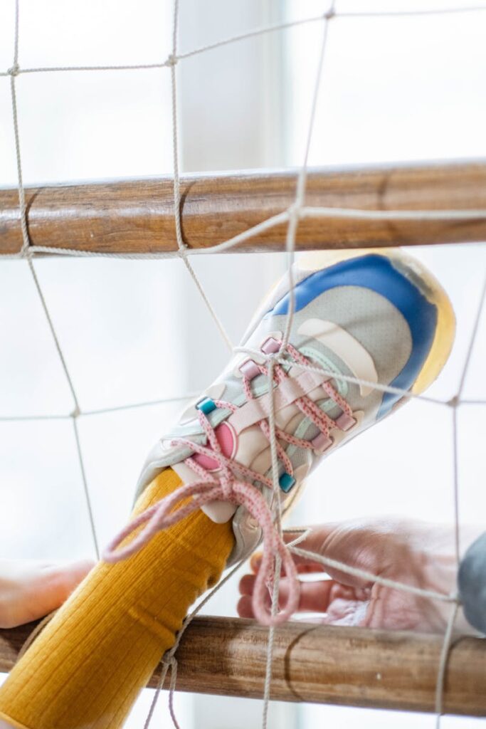 Close-up of a foot in a colorful shoe caught in a net, symbolizing entrapment.