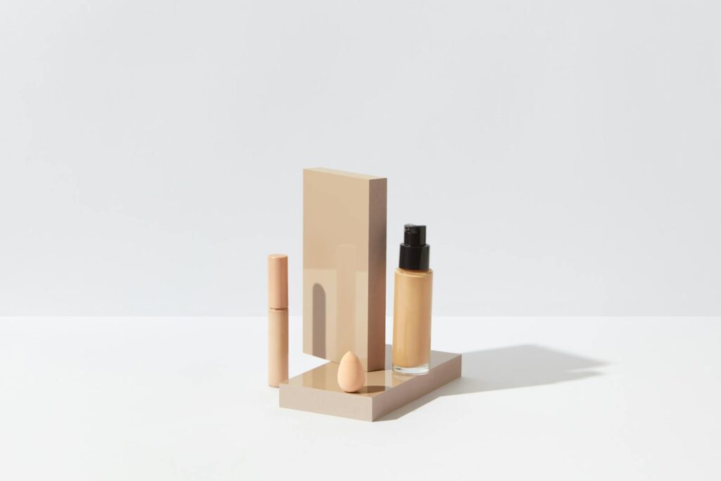 Elegant display of foundation, concealer, and sponge for a clean beauty setup on a white surface.