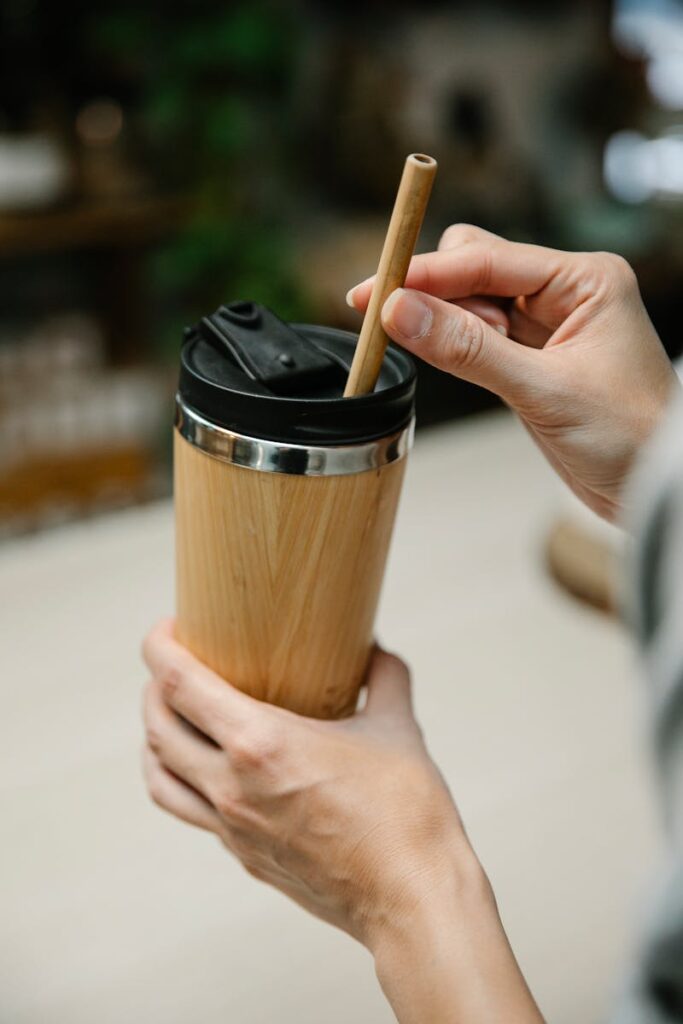 Eco-friendly bamboo tumbler with straw held by hands, promoting sustainability.