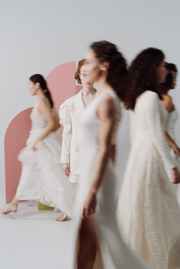 Fashion models walk in a studio, showcasing modern dresses in a blur, representing movement and diversity.