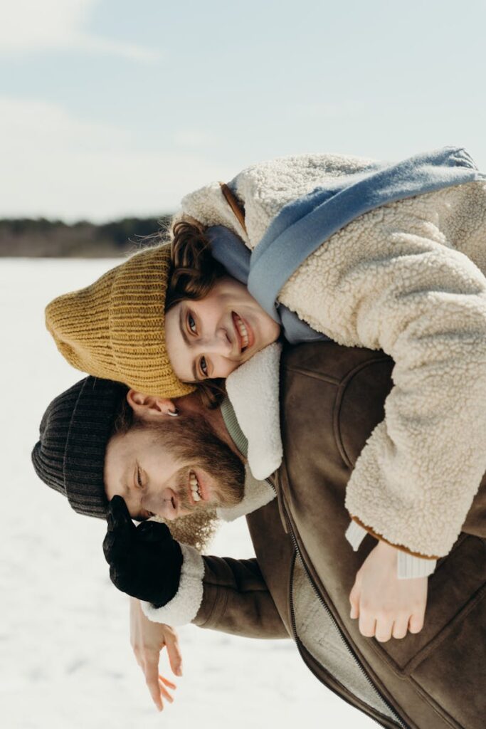 Smiling couple embracing in winter clothes outdoors, expressing happiness and love.