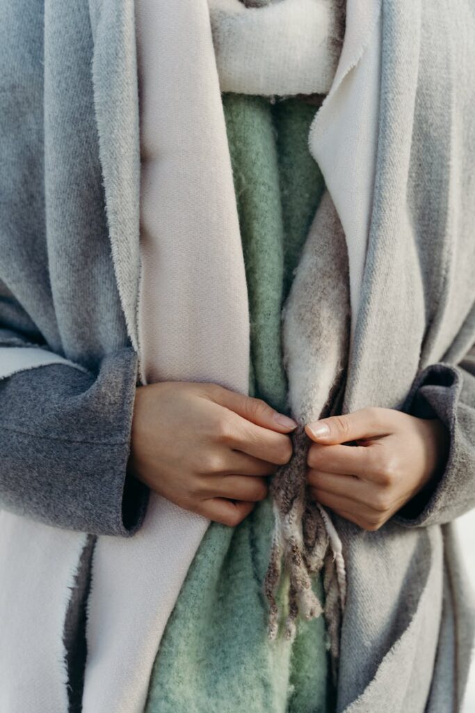 Woman in soft scarves and coat showcasing winter fashion layers.
