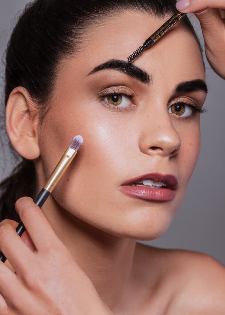 A detailed portrait showcasing makeup application with brushes on a woman's face.