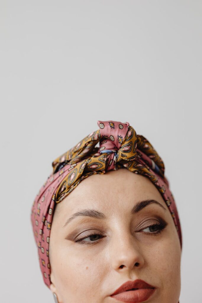 Close-up portrait of a woman wearing a colorful headscarf, showcasing fashion and confidence.