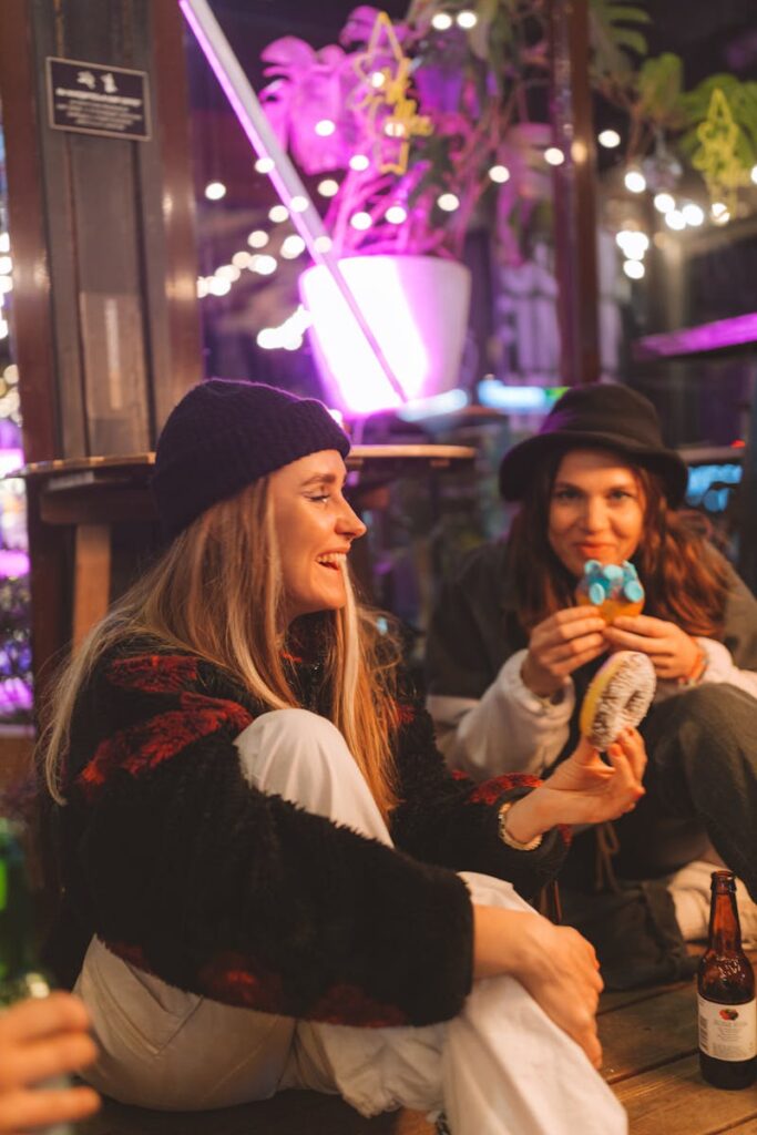 Two women enjoying a relaxed indoor gathering with snacks and drinks.