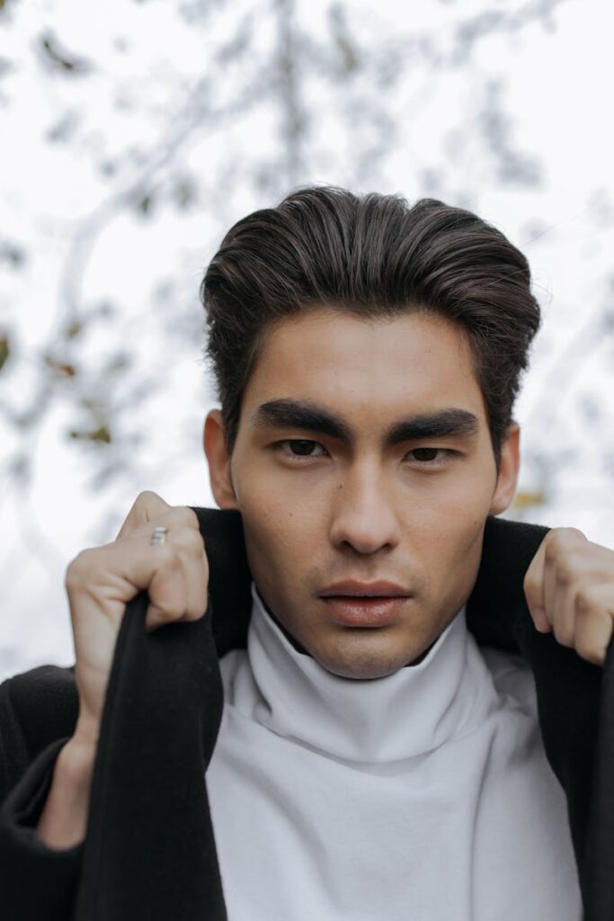 Close-up portrait of a serious man adjusting his coat outdoors, conveying confidence and style.
