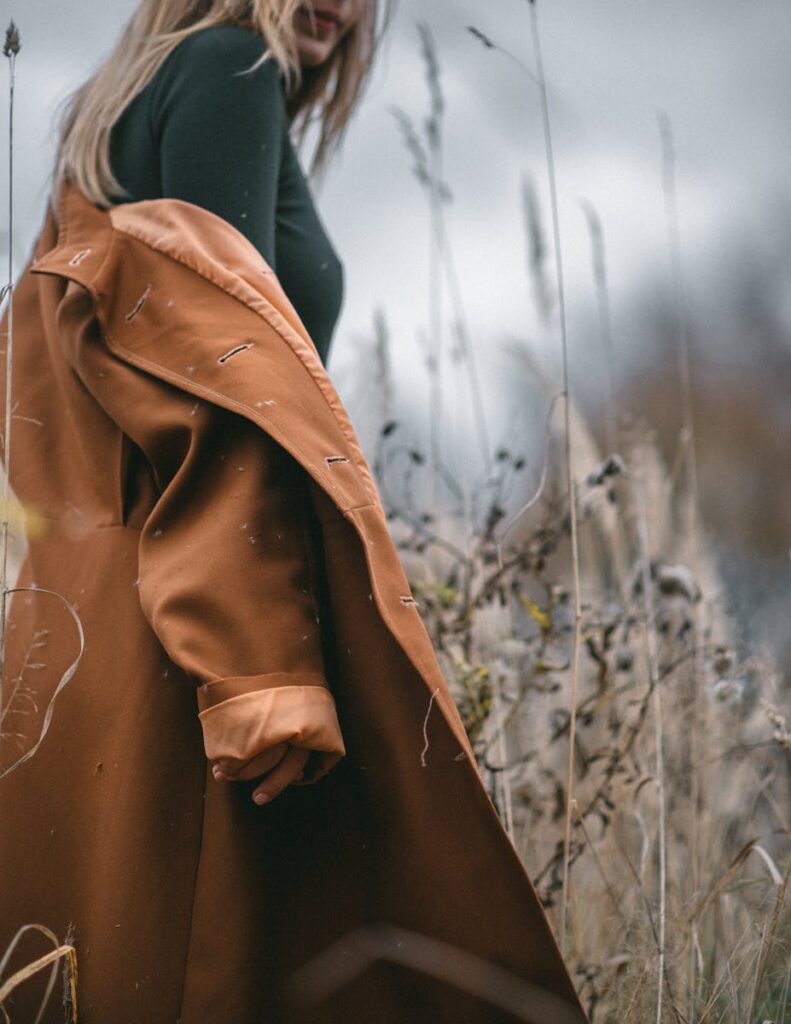 Woman in a stylish coat amidst a serene autumn meadow, embodying elegance and tranquility.