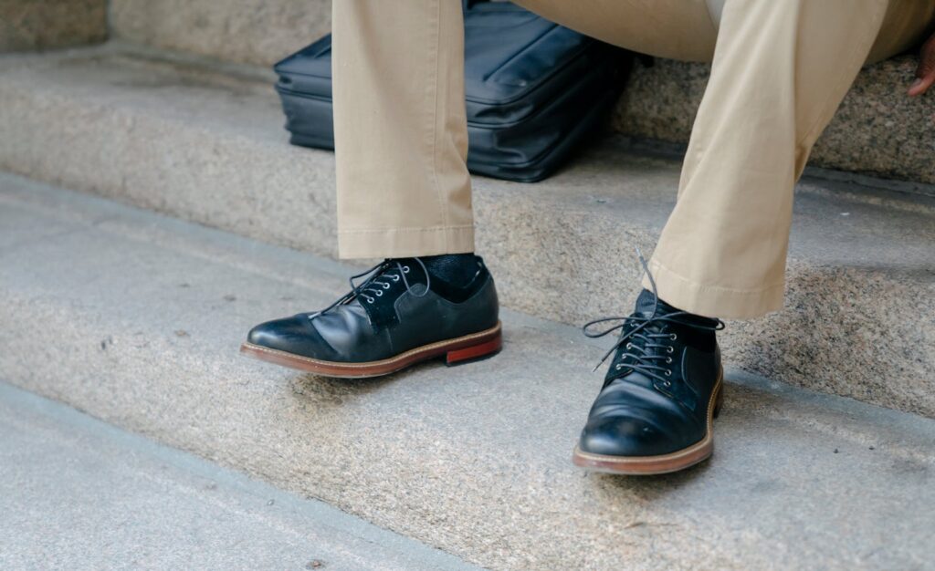 Close-up of elegant black leather shoes paired with khaki pants on outdoor steps.