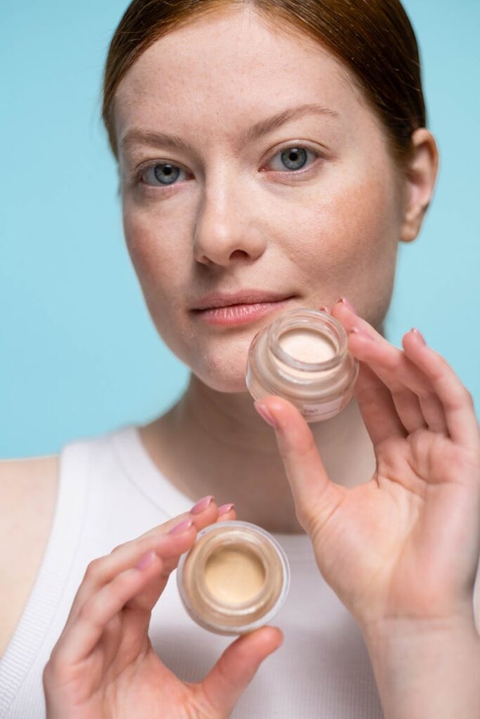 Woman showcasing skincare cream jar in a studio setting.