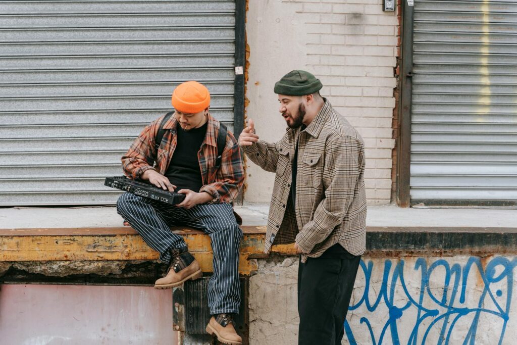 Two men interacting with a synthesizer against an urban backdrop.