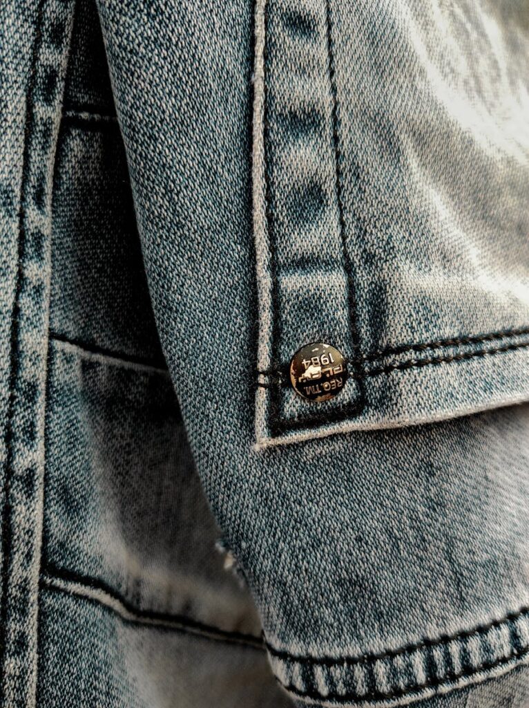 Detailed close-up of denim fabric showcasing seams and a metal button.
