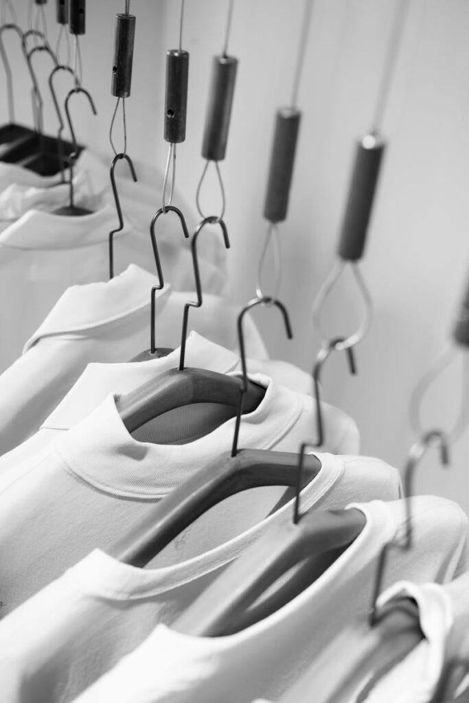 A stylish display of white clothes hanging on wooden hangers in a monochrome setting.