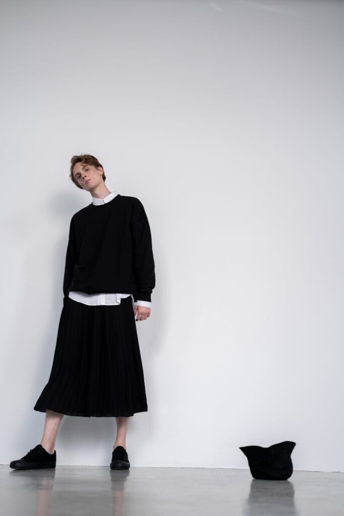 Stylish unisex fashion outfit with sweater and skirt in a studio portrait.