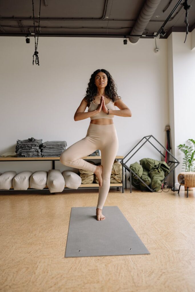 Woman performing a yoga pose indoors, showcasing wellness and balance in a serene studio environment.