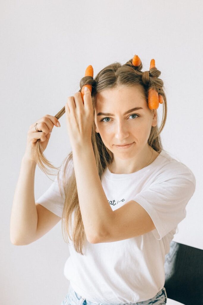Playful portrait of a young woman using carrots for hair styling at home.