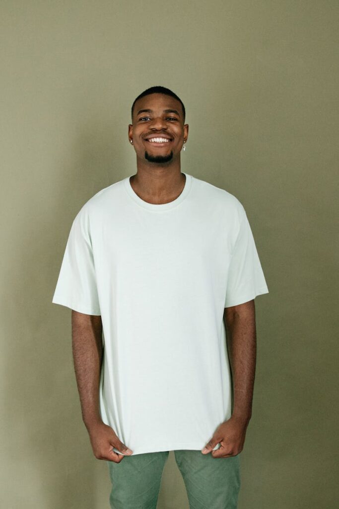 Portrait of a smiling man in a white t-shirt, posing casually against a plain background.